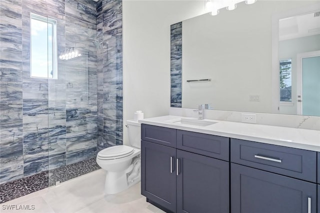 full bath with tiled shower, plenty of natural light, vanity, and toilet