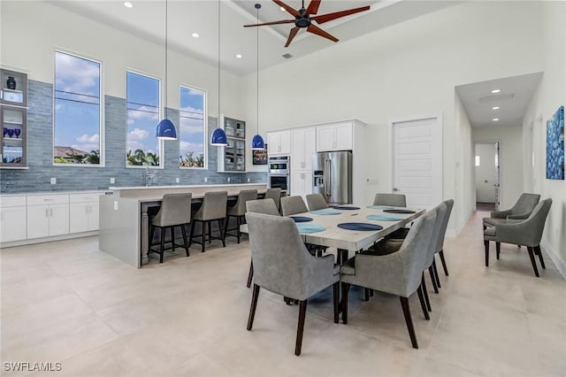 dining space with ceiling fan, a high ceiling, and recessed lighting