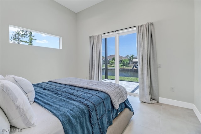 bedroom featuring a water view, access to exterior, multiple windows, and baseboards