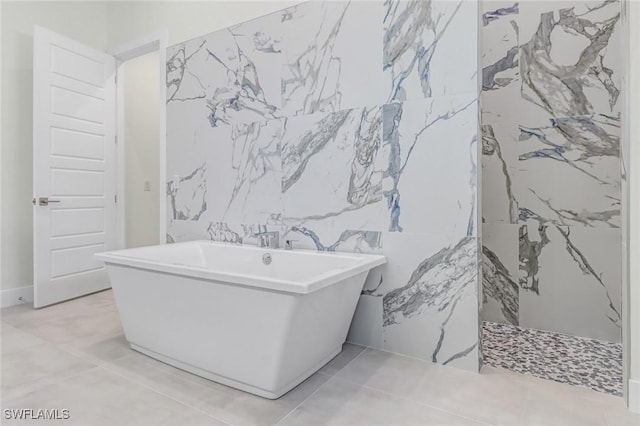 full bathroom featuring a freestanding tub, tile patterned flooring, and tile walls