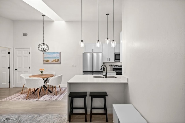 kitchen featuring white cabinetry, sink, hardwood / wood-style floors, a breakfast bar, and appliances with stainless steel finishes