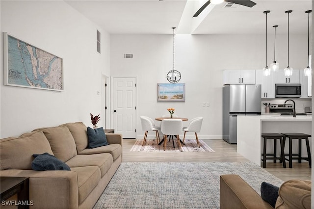 living room with a high ceiling, light hardwood / wood-style flooring, and ceiling fan