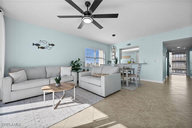 living room featuring light tile patterned floors and ceiling fan with notable chandelier