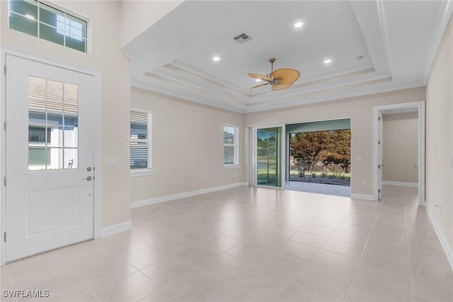 tiled entryway with a tray ceiling, ceiling fan, crown molding, and a healthy amount of sunlight