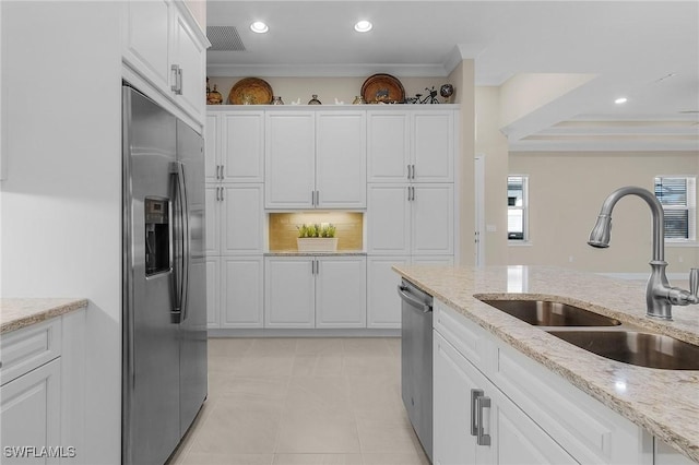 kitchen with light stone countertops, stainless steel appliances, crown molding, sink, and white cabinets