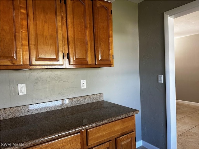 kitchen featuring light tile patterned floors and dark stone countertops