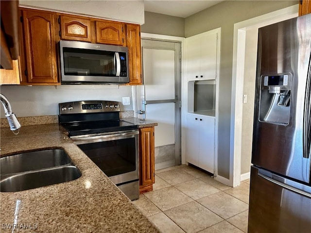 kitchen featuring stainless steel appliances, light stone countertops, sink, and light tile patterned floors