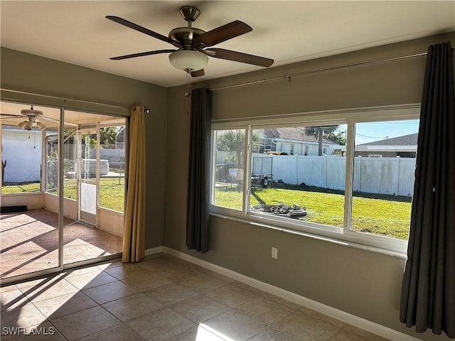 tiled spare room featuring ceiling fan and a wealth of natural light