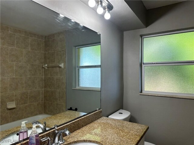 full bathroom featuring tiled shower / bath combo, vanity, and toilet