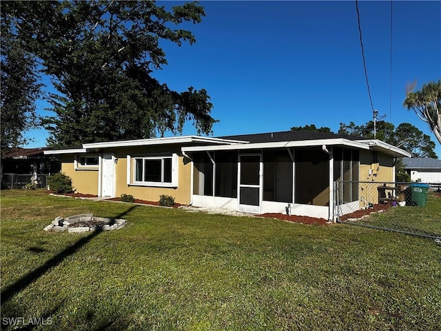 view of front of property featuring a sunroom, a fire pit, and a front lawn