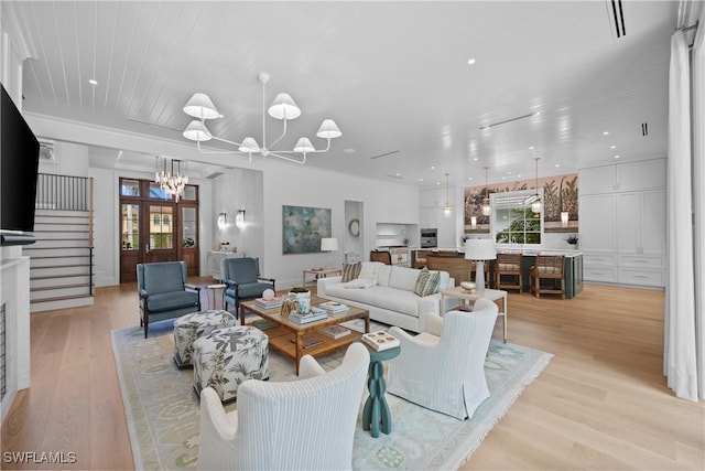 living room with a healthy amount of sunlight, a chandelier, and light wood-type flooring