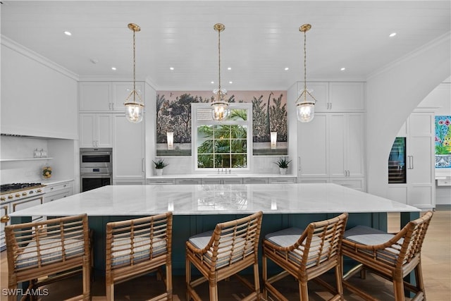 kitchen featuring pendant lighting, white cabinets, double oven, a large island, and a breakfast bar