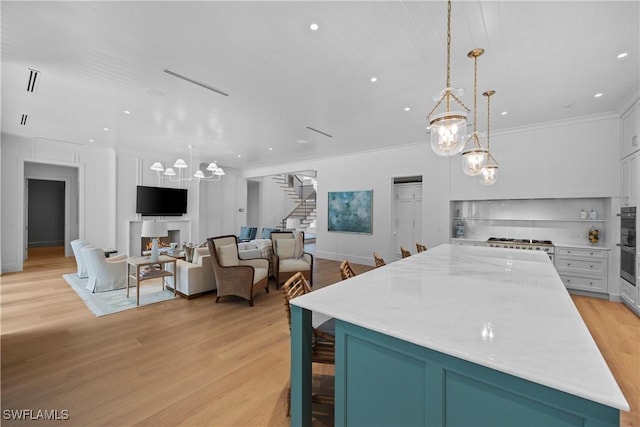 kitchen featuring pendant lighting, white cabinetry, an inviting chandelier, ornamental molding, and light hardwood / wood-style flooring