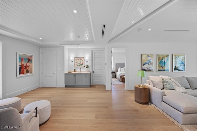 living room with sink, a raised ceiling, wood ceiling, and light wood-type flooring