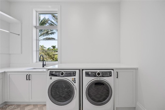 washroom with cabinets, separate washer and dryer, and sink