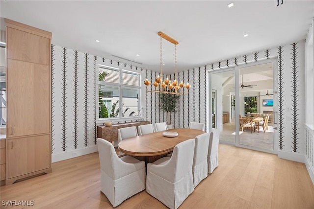 dining room featuring light hardwood / wood-style flooring and ceiling fan with notable chandelier