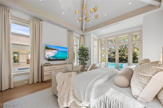 bedroom with a chandelier, light hardwood / wood-style flooring, and multiple windows