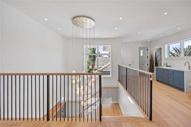 hall featuring sink, a chandelier, and light wood-type flooring