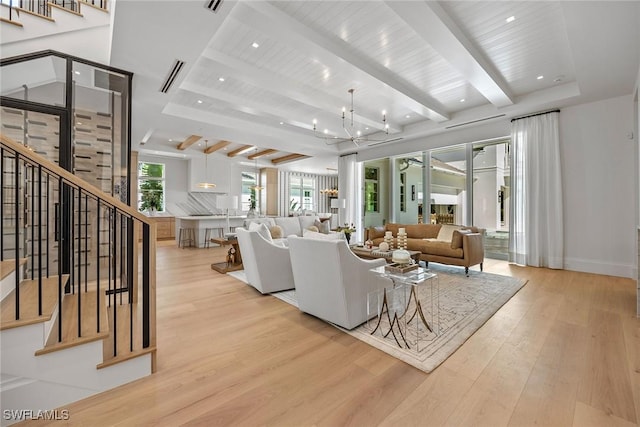 living room featuring beamed ceiling, light wood-type flooring, and an inviting chandelier