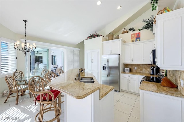 kitchen featuring stainless steel appliances, a kitchen island with sink, sink, white cabinetry, and lofted ceiling