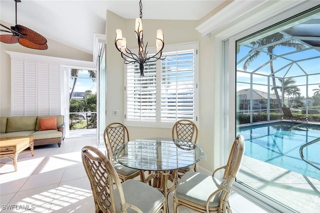 dining space featuring a wealth of natural light, light tile patterned floors, ceiling fan with notable chandelier, and vaulted ceiling