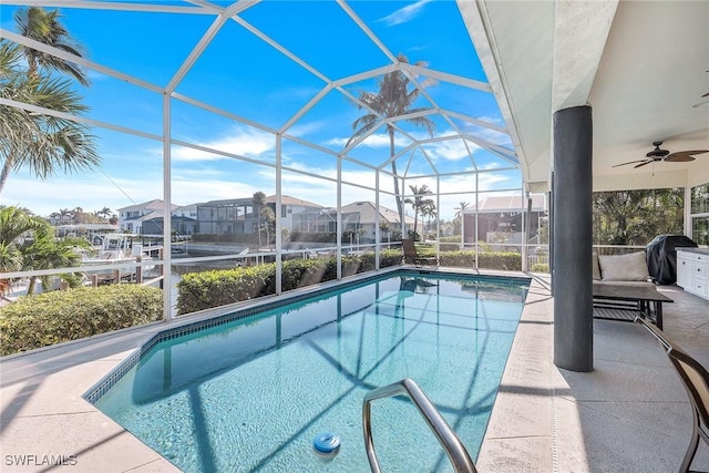 view of pool with glass enclosure, ceiling fan, a patio, and grilling area