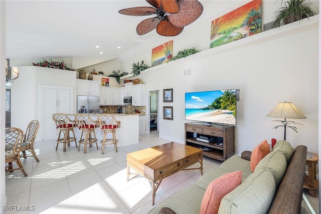 tiled living room with ceiling fan and a high ceiling