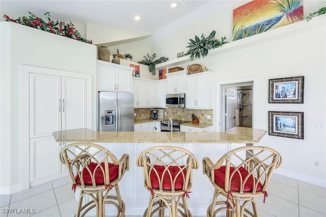 kitchen featuring white cabinets, appliances with stainless steel finishes, a spacious island, and a kitchen breakfast bar