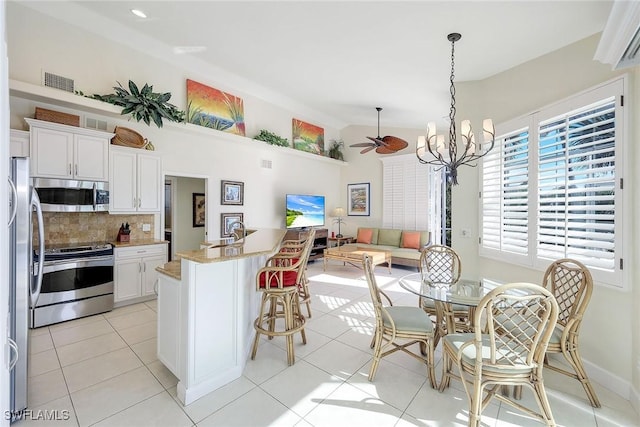 kitchen featuring light stone counters, stainless steel appliances, decorative light fixtures, white cabinetry, and light tile patterned flooring