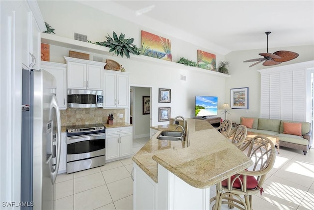 kitchen with white cabinetry, sink, stainless steel appliances, lofted ceiling, and a kitchen island with sink