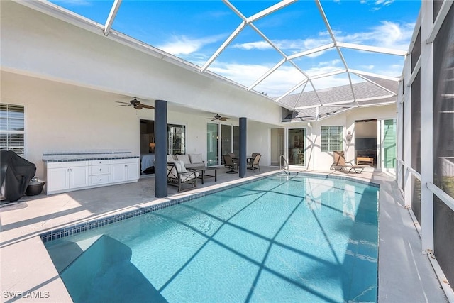 view of swimming pool featuring glass enclosure, ceiling fan, and a patio area