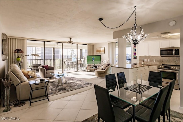 tiled dining area featuring ceiling fan with notable chandelier and plenty of natural light