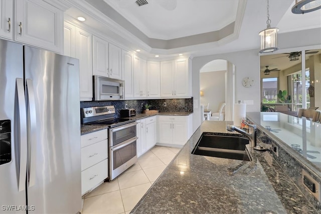 kitchen featuring sink, dark stone counters, pendant lighting, white cabinets, and appliances with stainless steel finishes