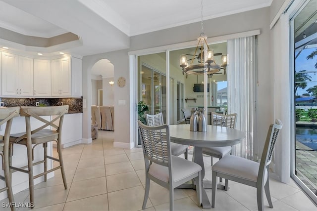 tiled dining room with crown molding and a chandelier