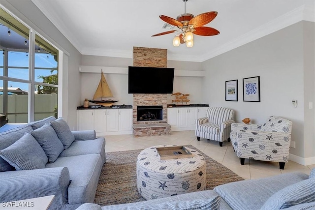 tiled living room featuring ceiling fan, a stone fireplace, and crown molding