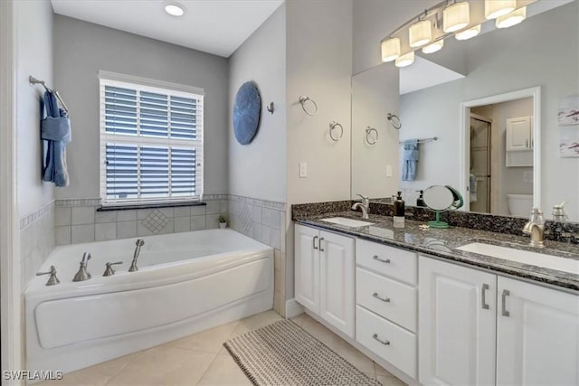 bathroom with a washtub, vanity, tile patterned floors, and toilet