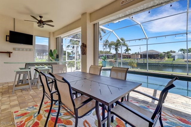 exterior space with ceiling fan, a water view, a bar, and glass enclosure