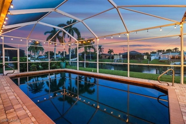 pool at dusk with a water view and glass enclosure