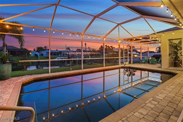 pool at dusk featuring a water view and a lanai