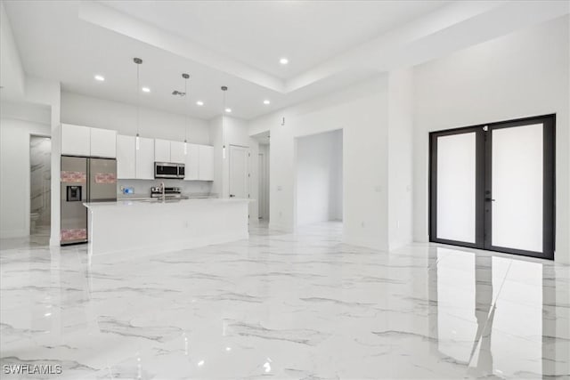 kitchen featuring sink, an island with sink, pendant lighting, white cabinets, and appliances with stainless steel finishes