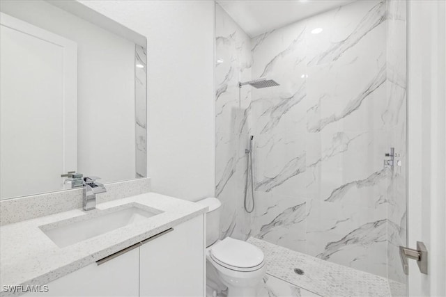 bathroom with a tile shower, vanity, and toilet