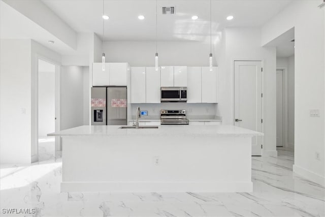 kitchen featuring white cabinetry, sink, stainless steel appliances, pendant lighting, and a kitchen island with sink