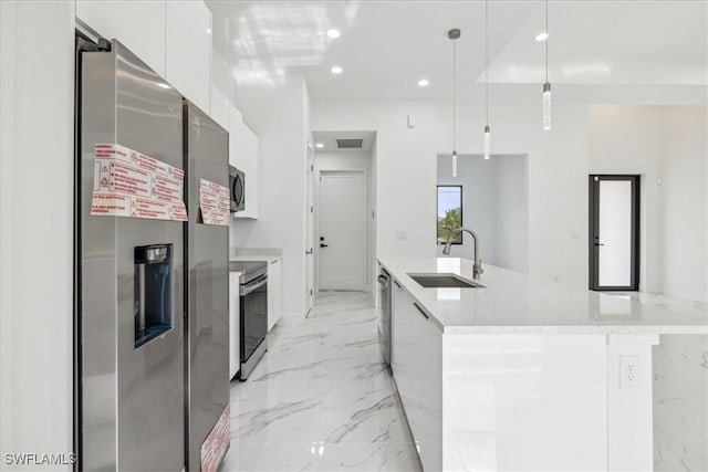 kitchen featuring stainless steel appliances, sink, pendant lighting, a center island with sink, and white cabinets