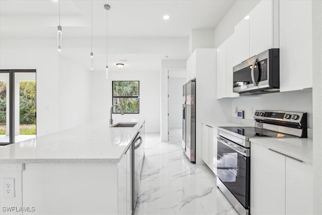 kitchen with a kitchen island with sink, sink, hanging light fixtures, white cabinetry, and stainless steel appliances