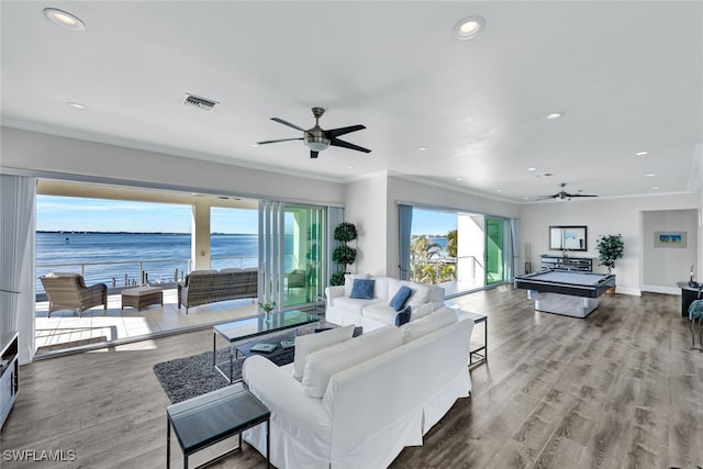 living room with a water view, wood-type flooring, and ornamental molding