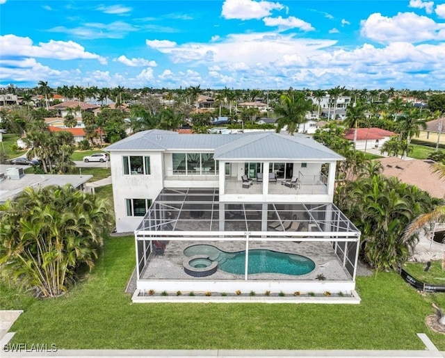 back of house featuring a swimming pool with hot tub, a yard, a balcony, and a patio area