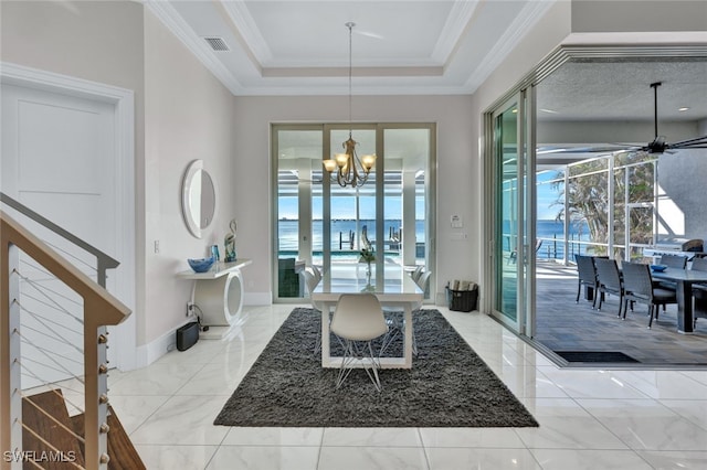 foyer with a tray ceiling, a water view, ceiling fan with notable chandelier, and ornamental molding