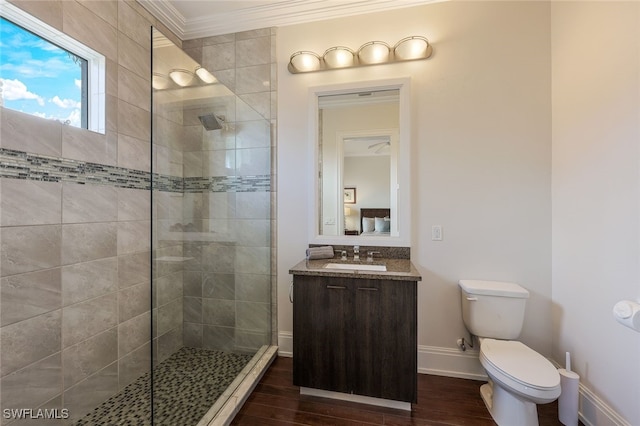 bathroom with crown molding, tiled shower, toilet, vanity, and hardwood / wood-style flooring