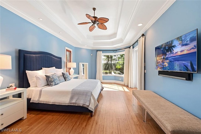 bedroom featuring light wood-type flooring, a raised ceiling, ceiling fan, and ornamental molding