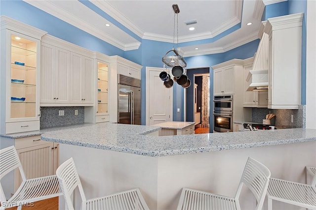 kitchen featuring kitchen peninsula, white cabinetry, decorative light fixtures, and appliances with stainless steel finishes